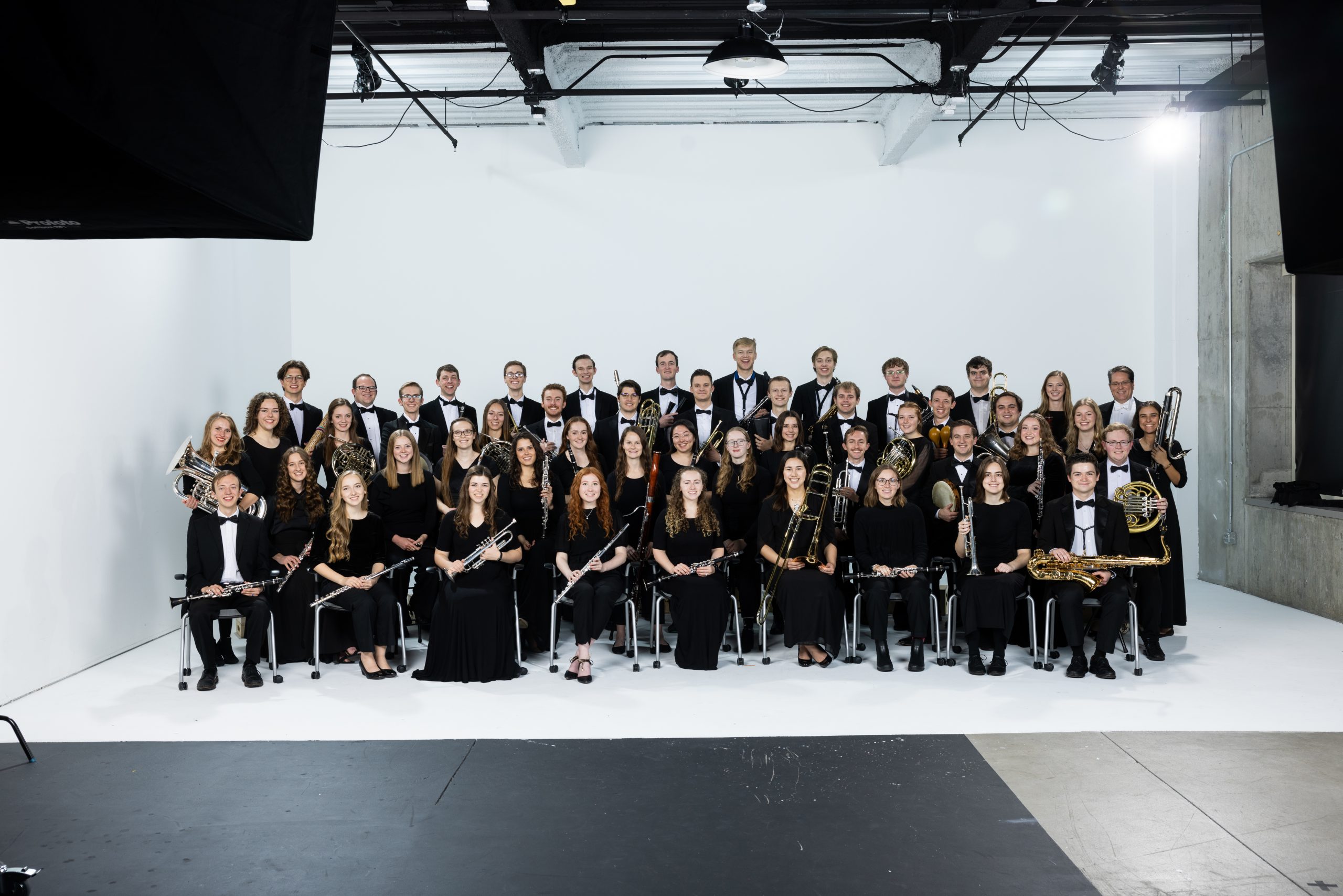 BYU Wind Symphony gathered in concert black with their instruments against a white studio backdrop