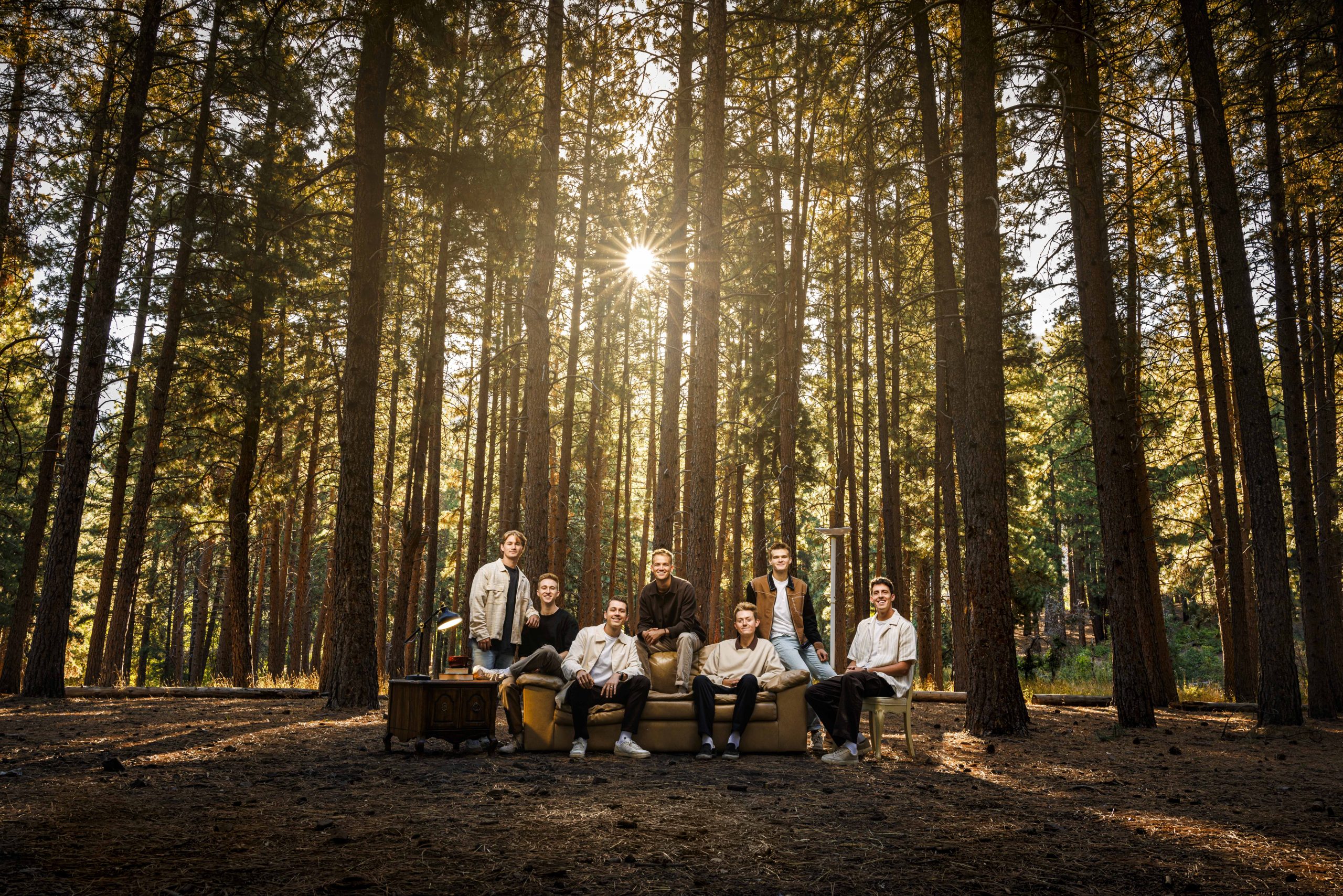 Vocal Point members gather around a couch in the Payson Canyon, surrounded by trees.