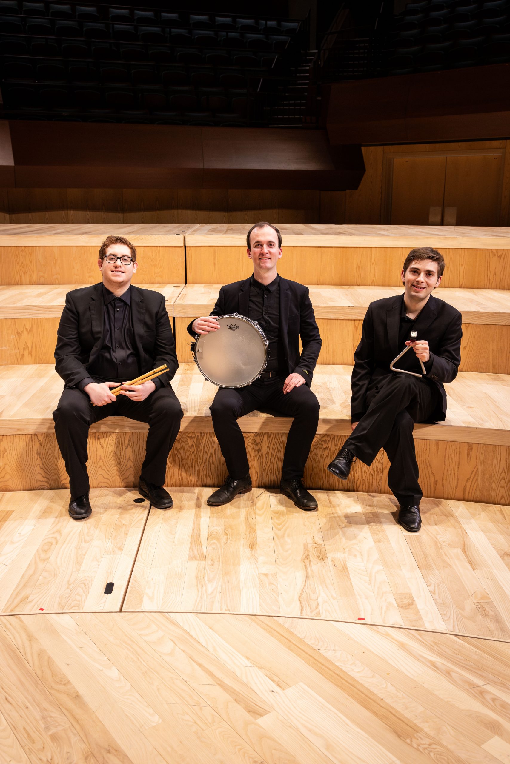 BYU Chamber Orchestra percussion section sits on concert hall steps with instruments