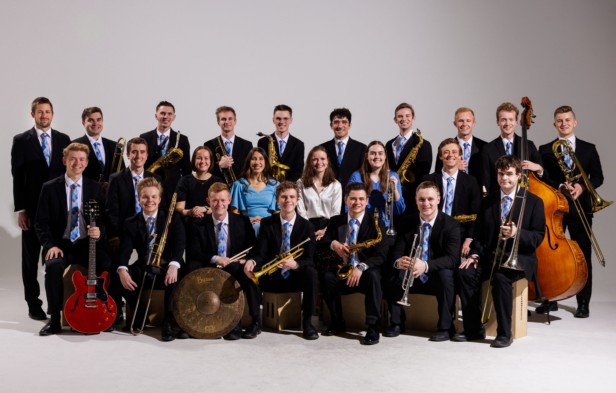BYU Synthesis gathers as a group in formal dress with their instruments against a white, studio background